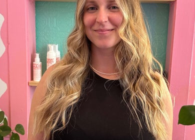 Carly Jones salon in Victoria, British Columbia, CA with a smiling customer and hair products displayed.