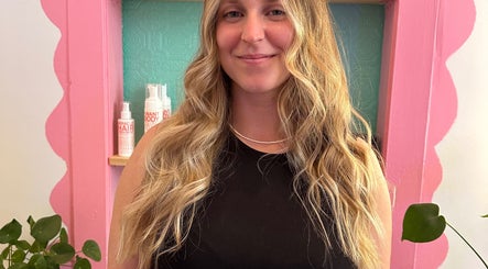 Carly Jones salon in Victoria, British Columbia, CA with a smiling customer and hair products displayed.