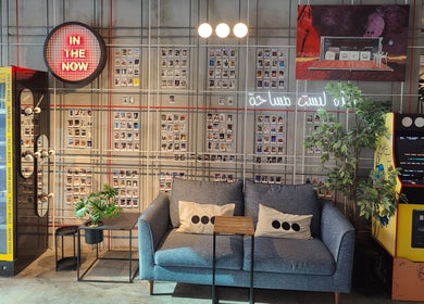 Chic lounge in Not a Space, Sharjah, AE with arcade machine, couch, and neon decor.