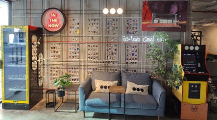 Chic lounge in Not a Space, Sharjah, AE with arcade machine, couch, and neon decor.