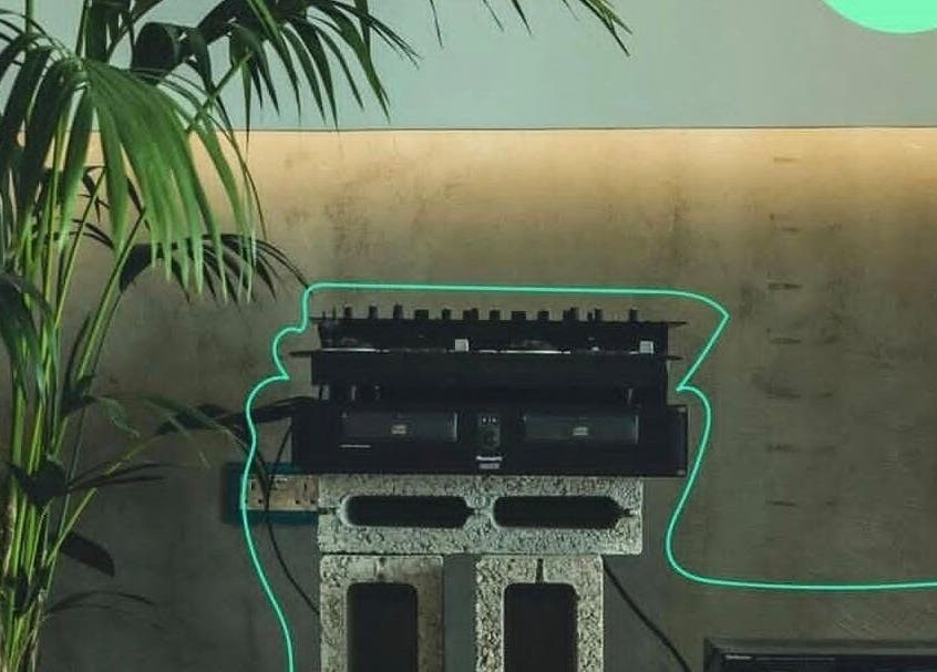 Neon glow around DJ set at Not a Space, Sharjah, AE with a lush palm in the background.