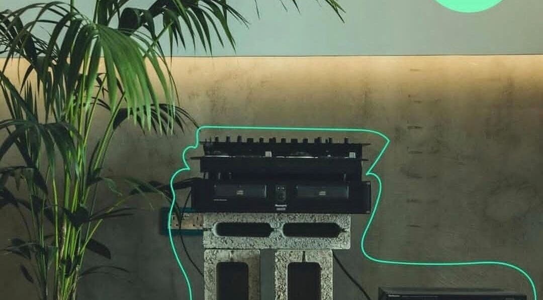 Neon glow around DJ set at Not a Space, Sharjah, AE with a lush palm in the background.