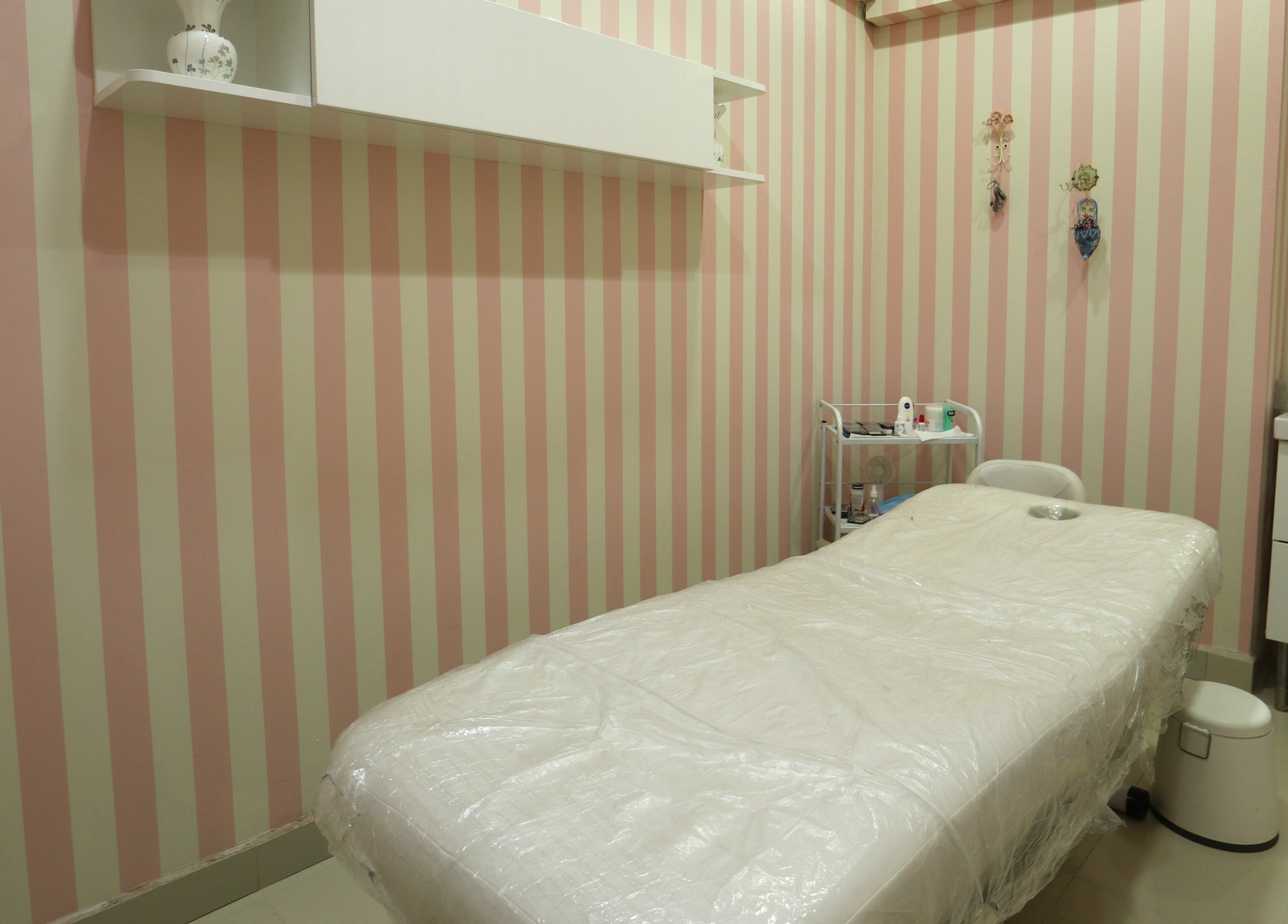 Cozy treatment room at Vivian Beauty Center in دبي, دبي, AE with a striped pink wall and a massage table.