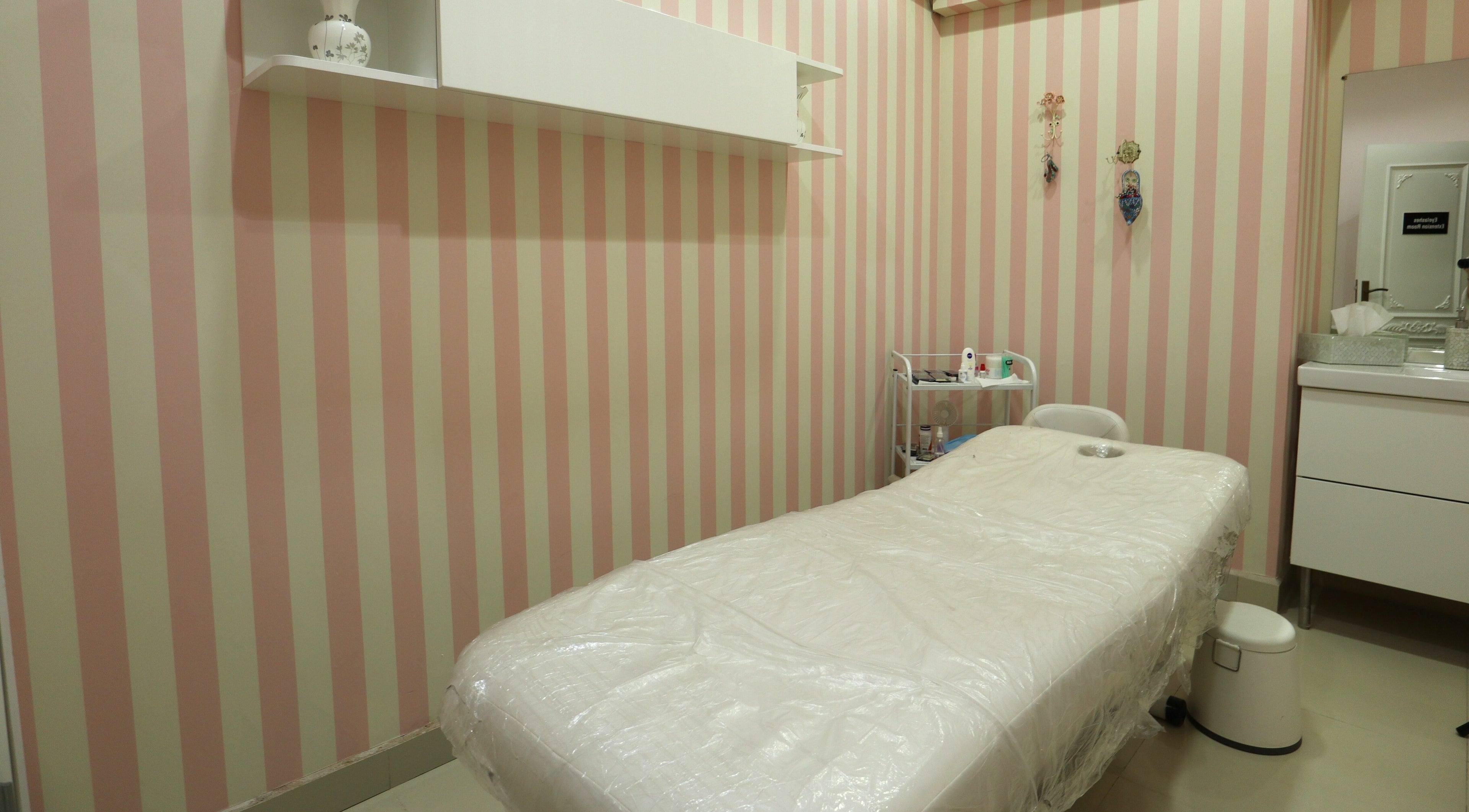 Cozy treatment room at Vivian Beauty Center in دبي, دبي, AE with a striped pink wall and a massage table.