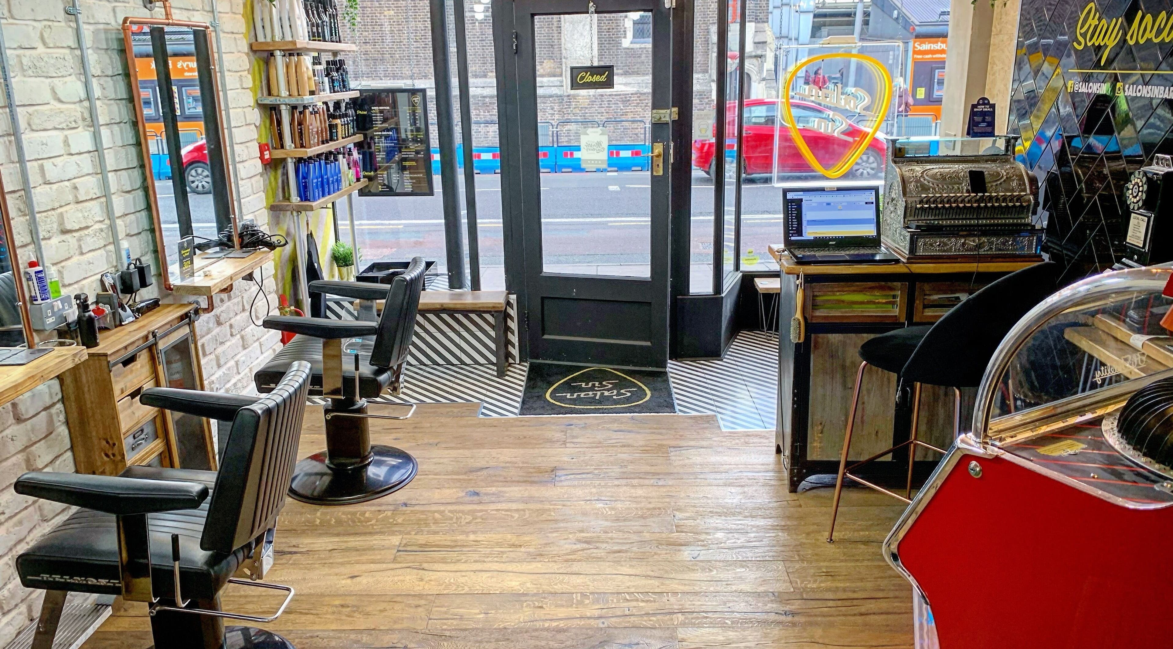 Interior of Salon Sin in London, England, GB, featuring stylish chairs, vintage decor, and urban street view.