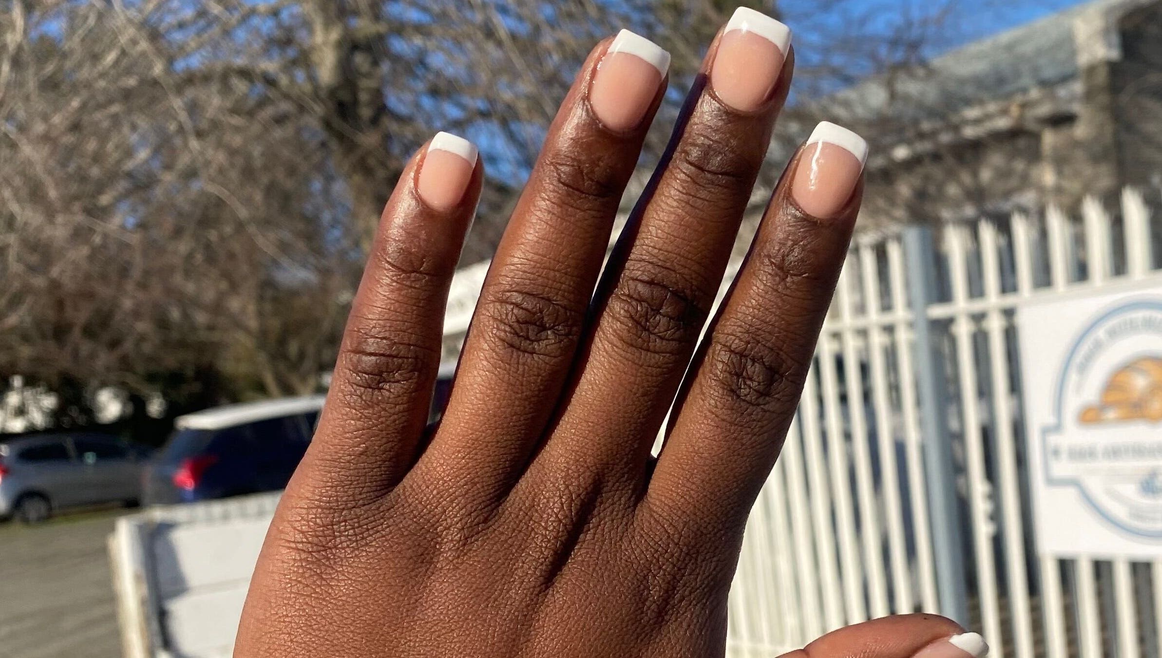 Hand with elegant French manicure outside Nail & Beauty Creations, Cape Town, Western Cape, ZA.
