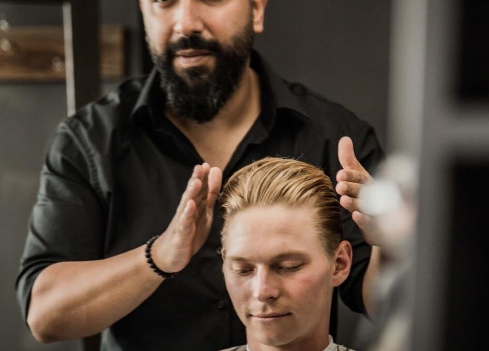 Stylist at The Barberchop in Cape Town, Western Cape, ZA, perfecting a sleek hairstyle for a client.