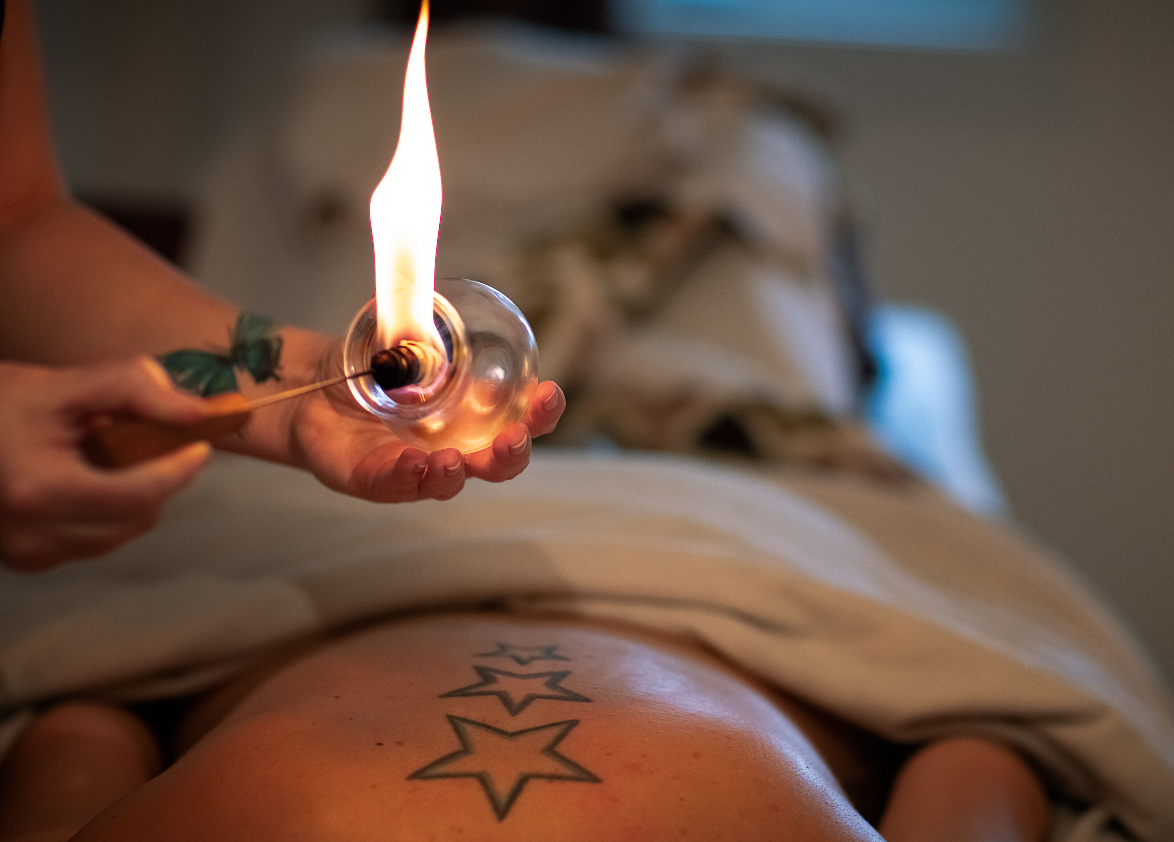 Fire massage therapy at Healing With Dawn, Collingwood, Ontario, CA, featuring a unique star tattoo.