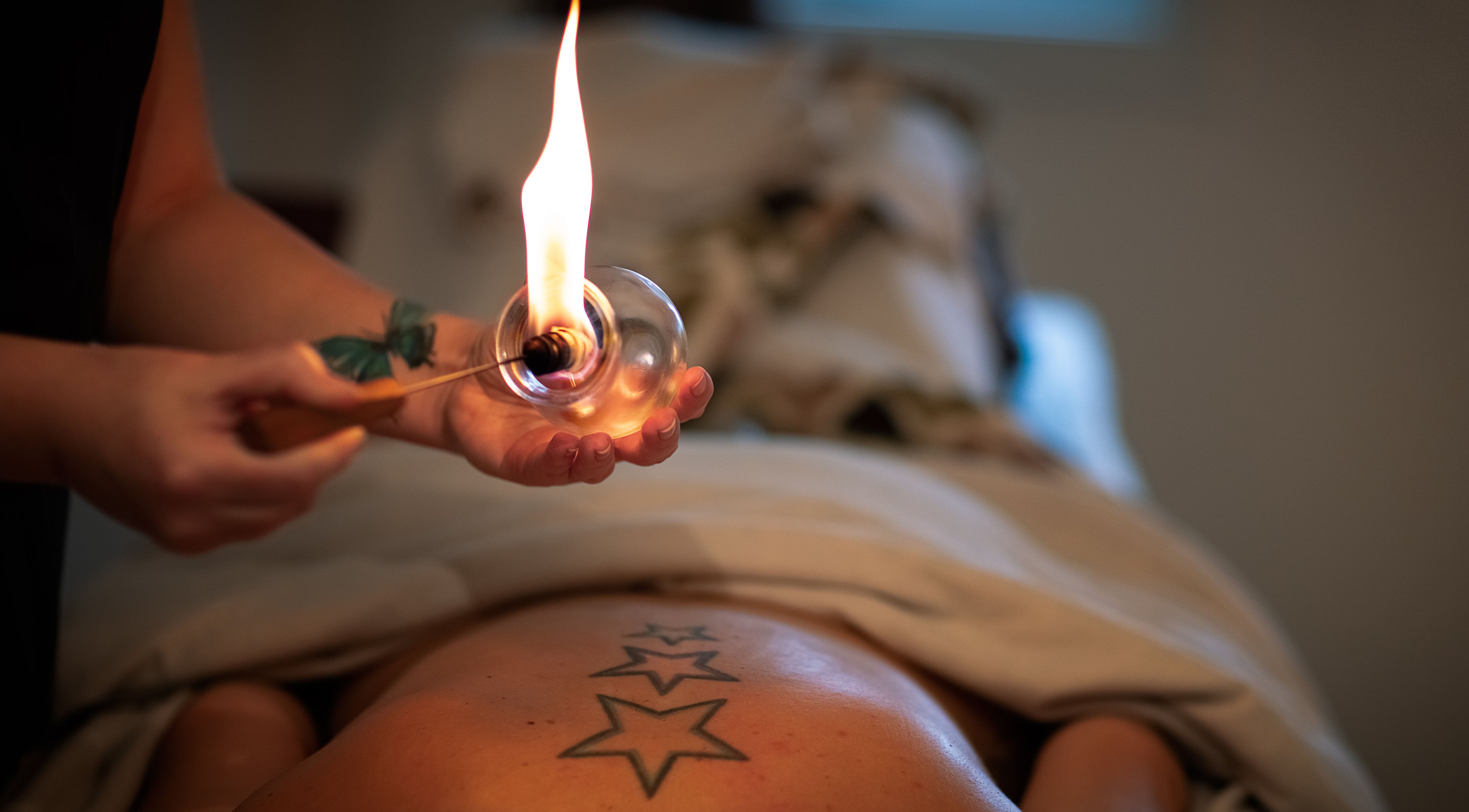 Fire massage therapy at Healing With Dawn, Collingwood, Ontario, CA, featuring a unique star tattoo.