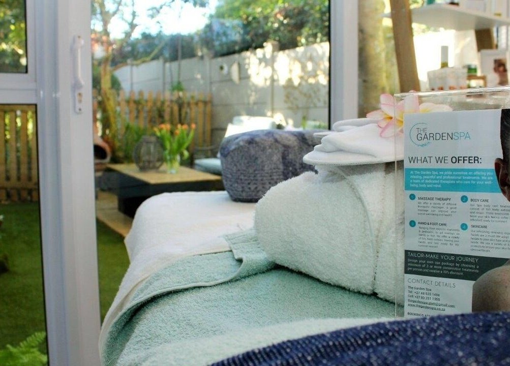 Relaxing spa room at The Garden Spa, Plettenberg Bay, Western Cape, ZA, with lush garden view and massage table.