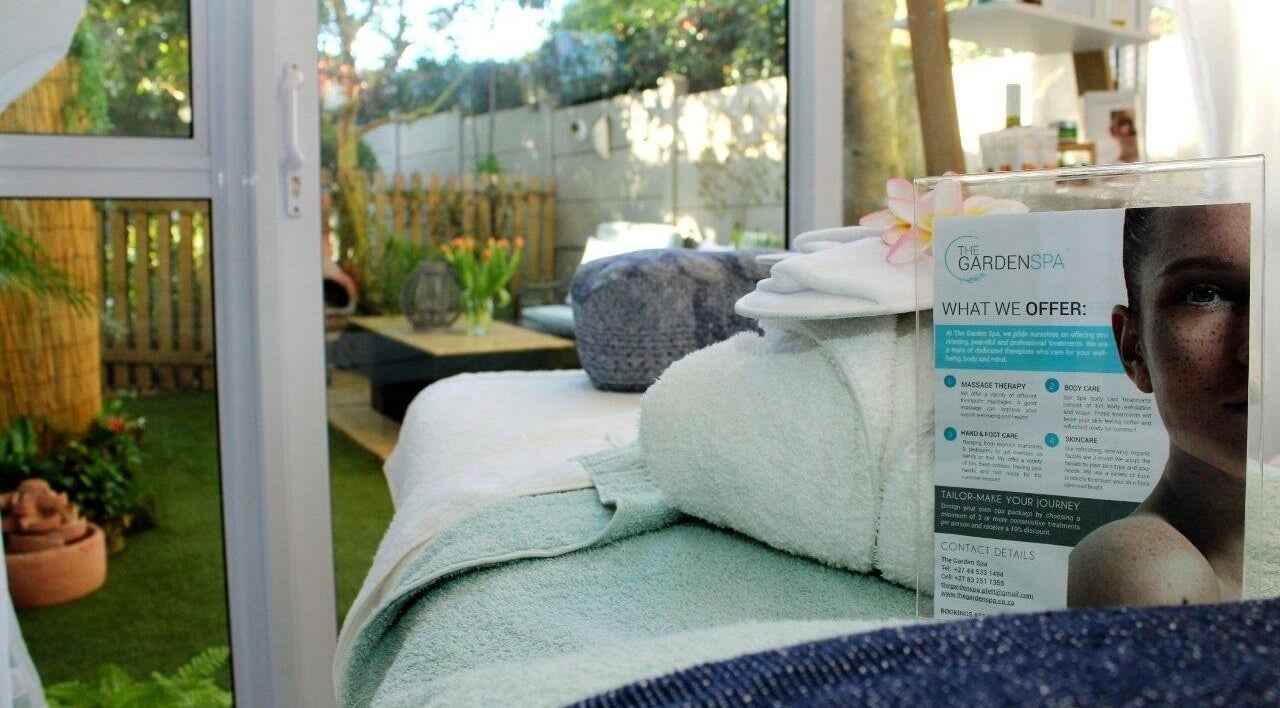 Relaxing spa room at The Garden Spa, Plettenberg Bay, Western Cape, ZA, with lush garden view and massage table.
