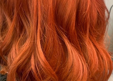 Vibrant red curls styled at Clara Devlin Hair, Cardington, England, GB, showcasing rich color and texture.
