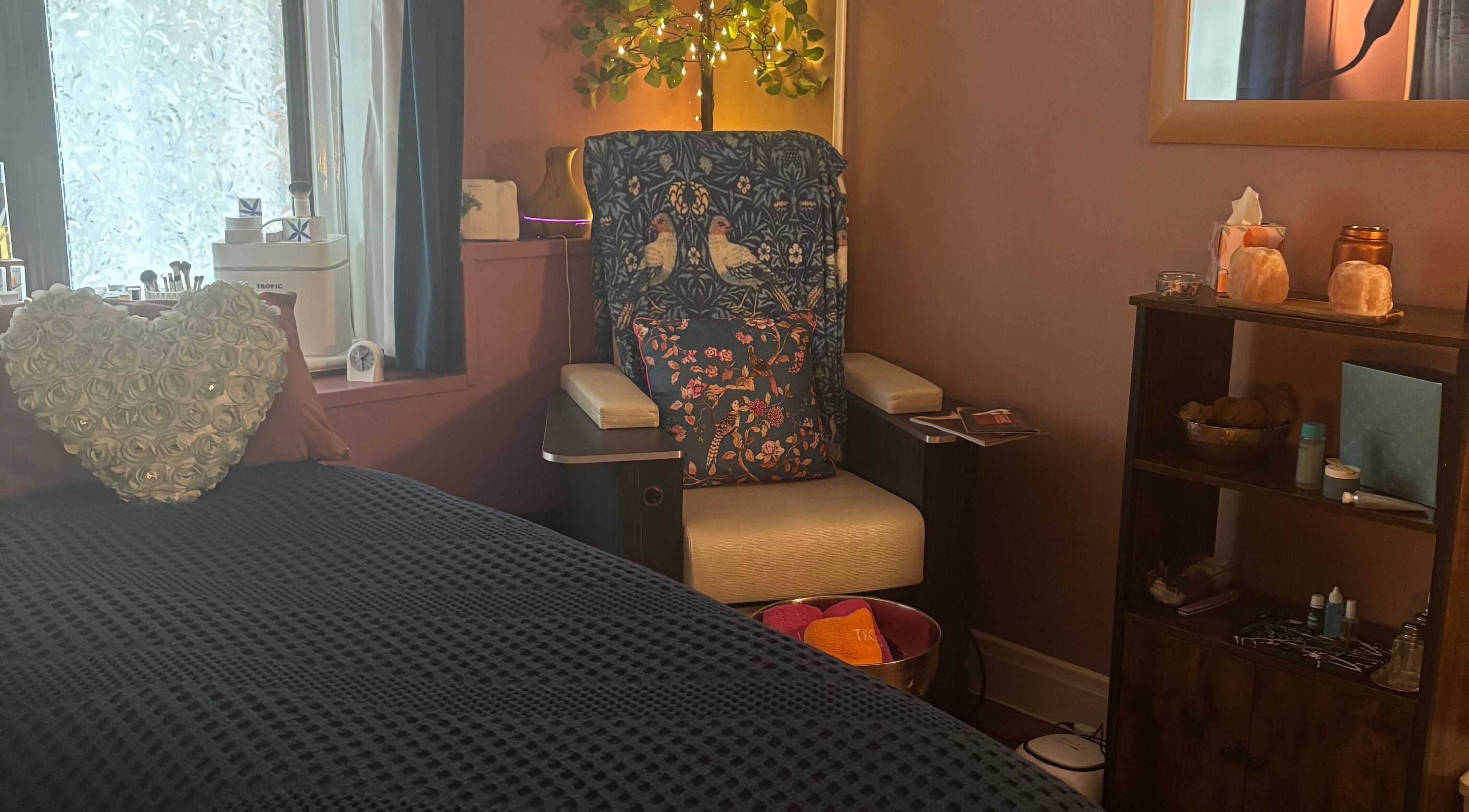 Relaxing corner at Beauty By The Quay, Ramsey, Isle of Man, IM, featuring a plush chair and heart-shaped cushion.