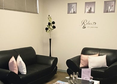 Elegant waiting area at Beauty by Nadia in Pretoria, Gauteng, ZA with cozy black sofas and chic decor.