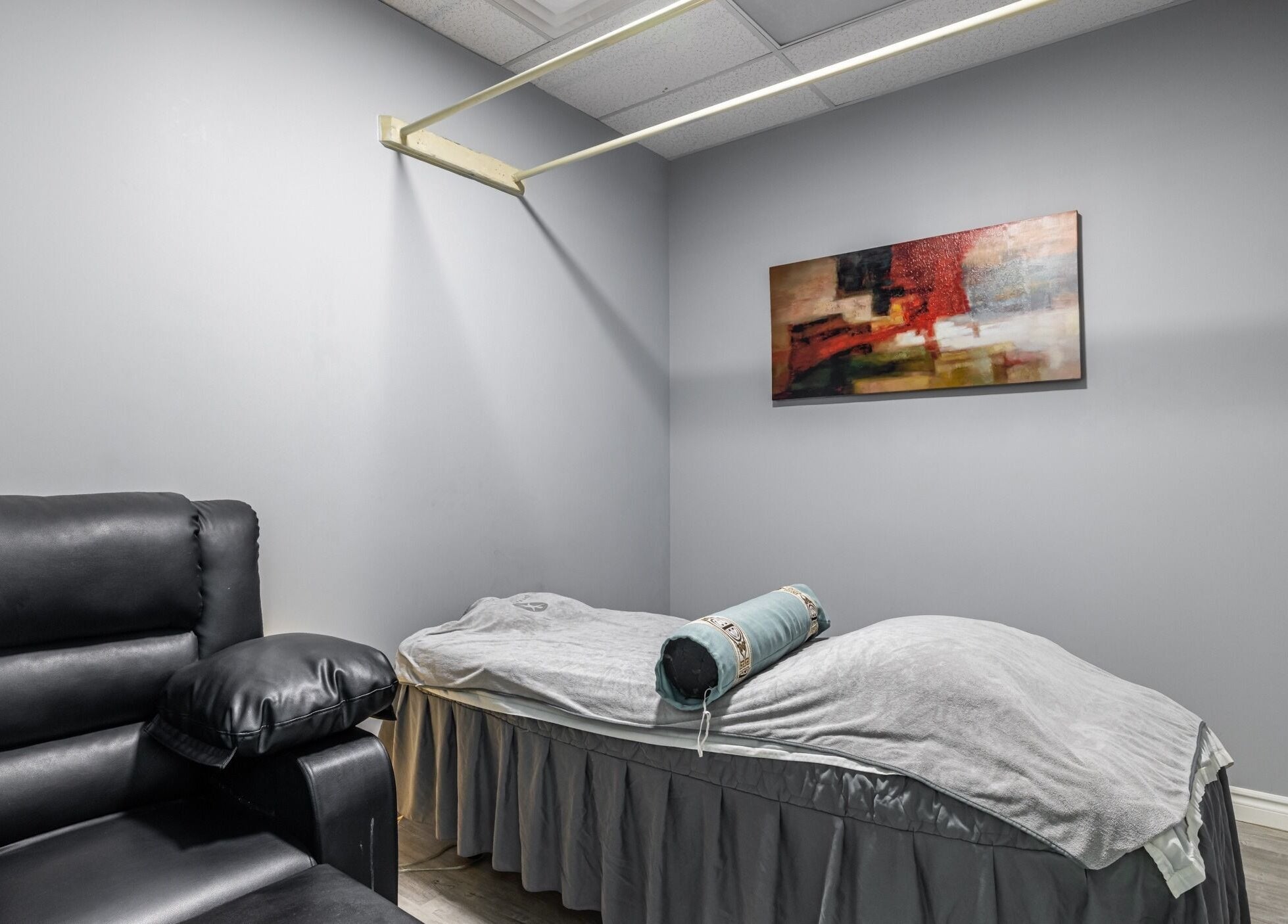 Relaxing massage room at A-Plus Rehab in Toronto, Ontario, CA featuring a plush chair and treatment bed.