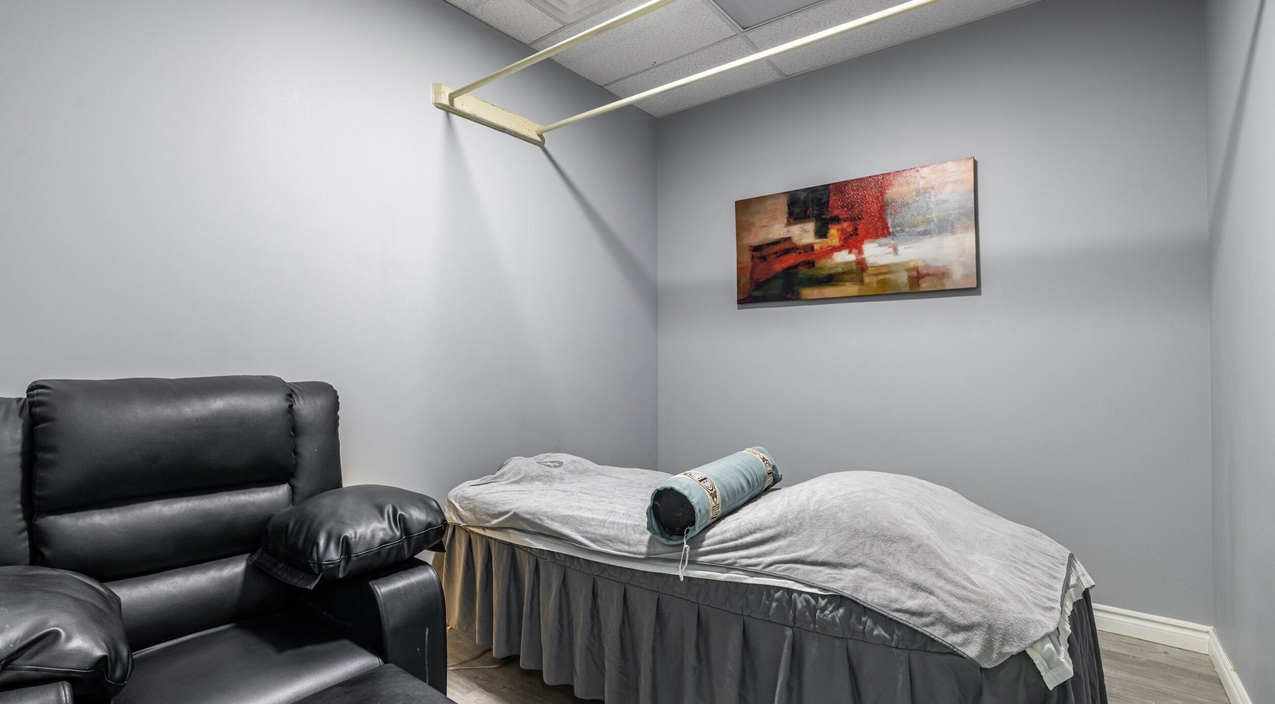 Relaxing massage room at A-Plus Rehab in Toronto, Ontario, CA featuring a plush chair and treatment bed.