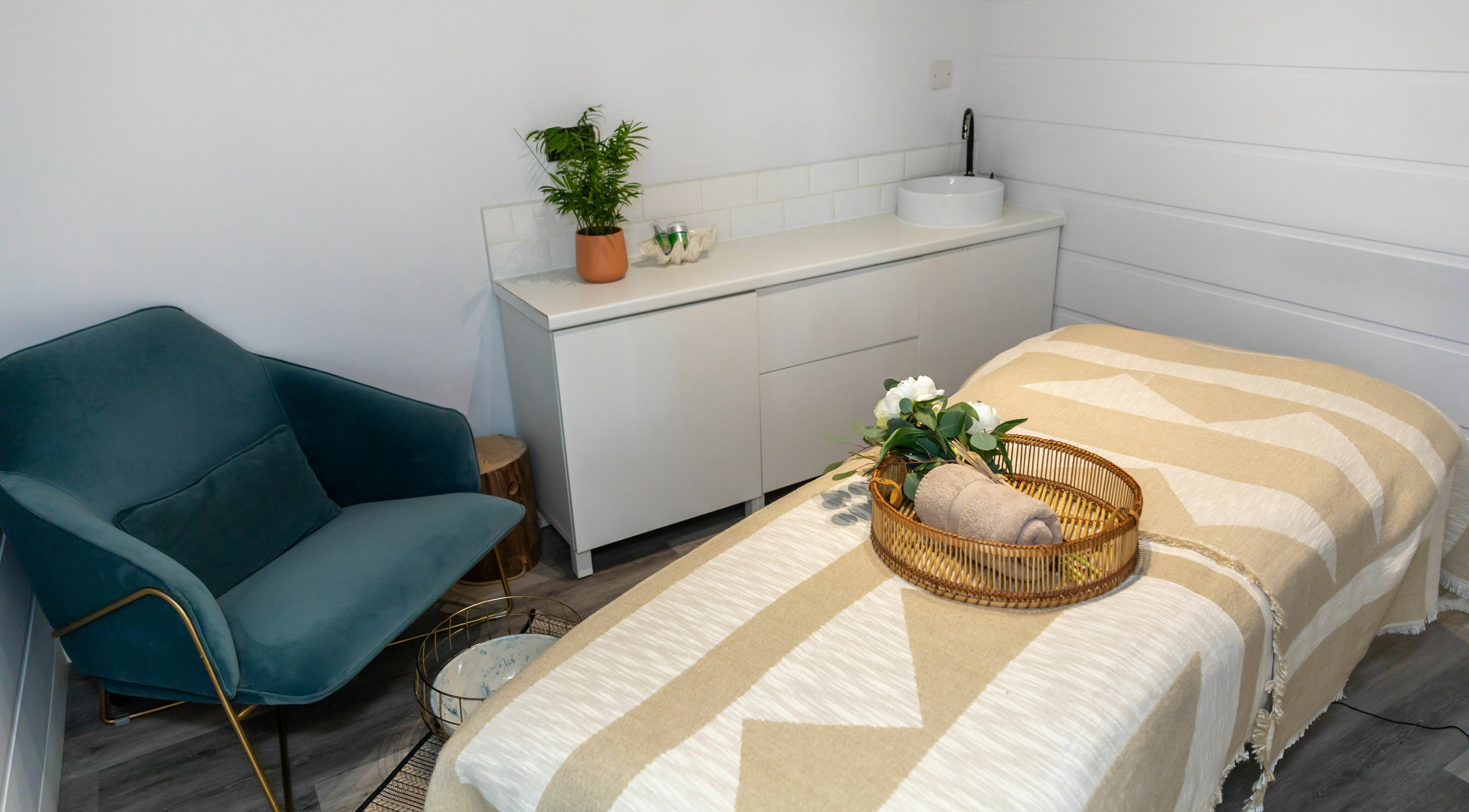Peaceful treatment room at The Spa Club, Arundel, England, GB with cozy chair, sleek sink, and a soft treatment bed.