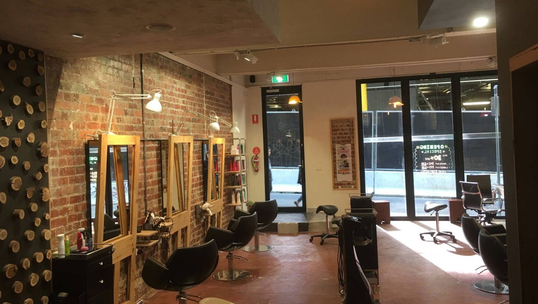 Stylish interior of Salon Atreve in Melbourne, VIC, AU with brick walls and modern salon stations.