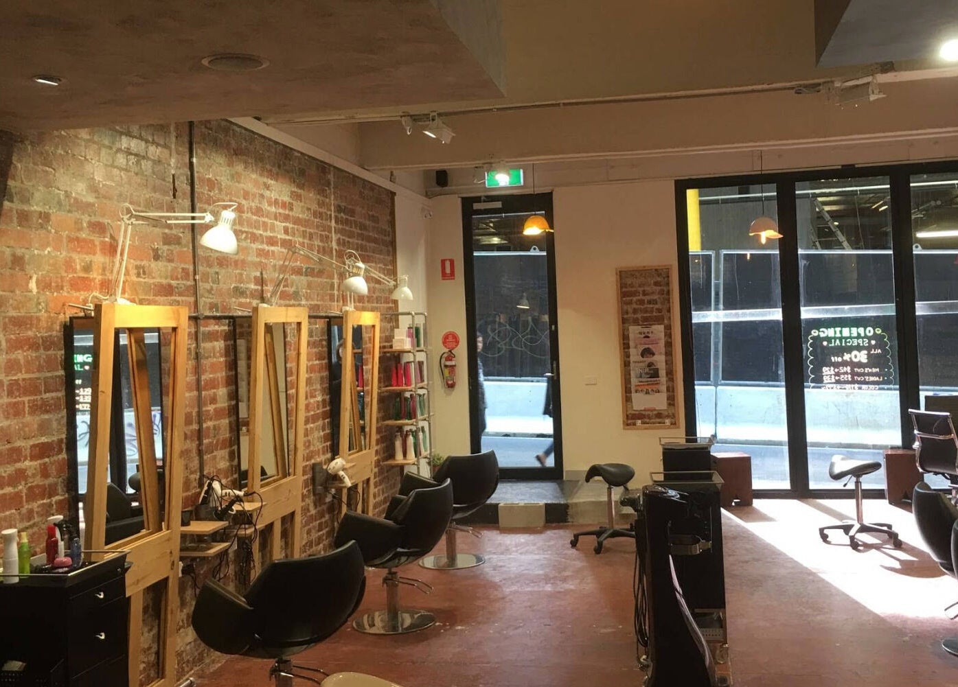Stylish interior of Salon Atreve in Melbourne, VIC, AU with brick walls and modern salon stations.