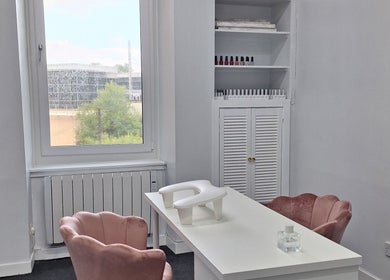 Elegant nail station at Nails Quoture in Glasgow, Scotland, GB, featuring plush pink chairs and nail polish display.