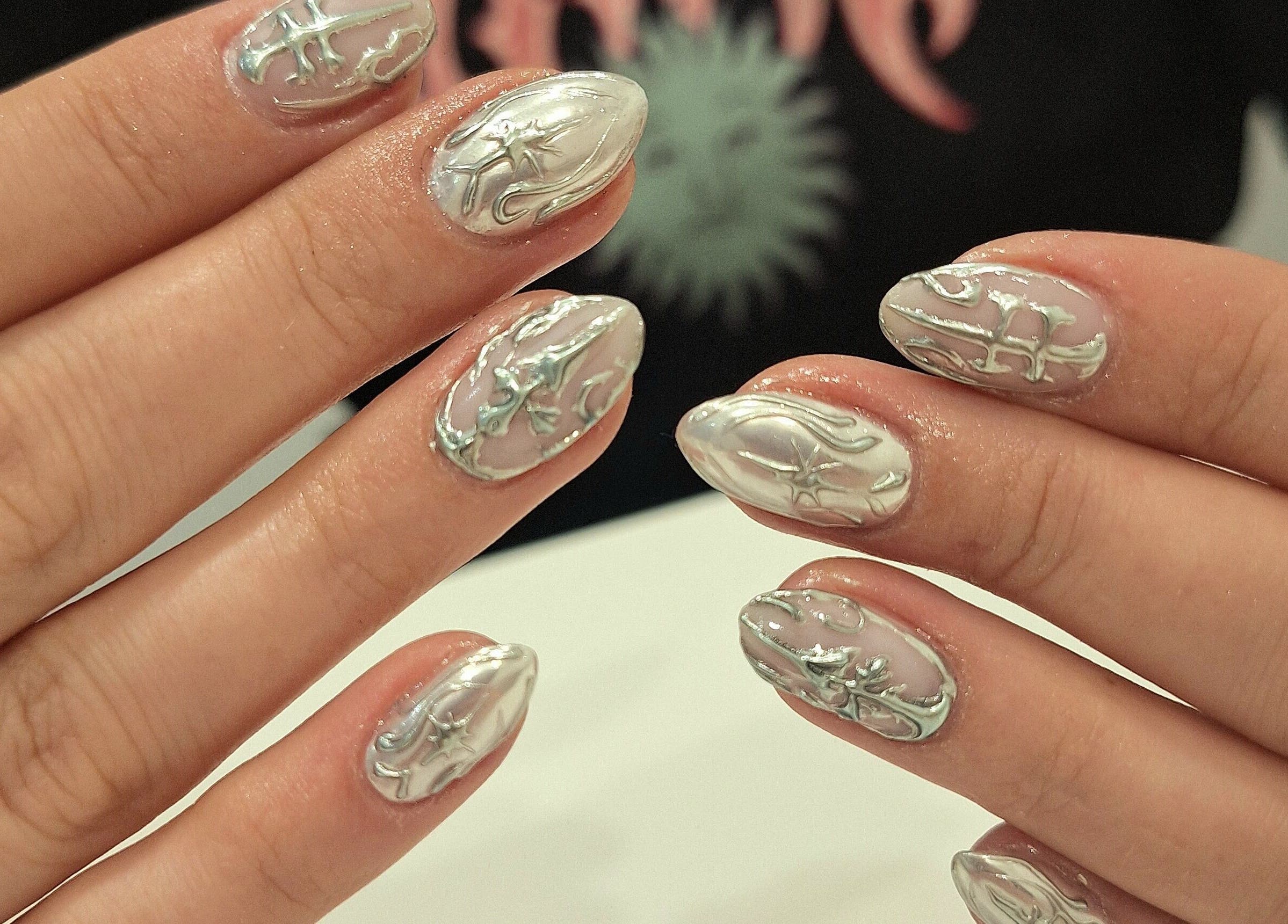 Intricate silver nail art at Nails Quoture, Glasgow, Scotland, GB showcases artistic nail designs.