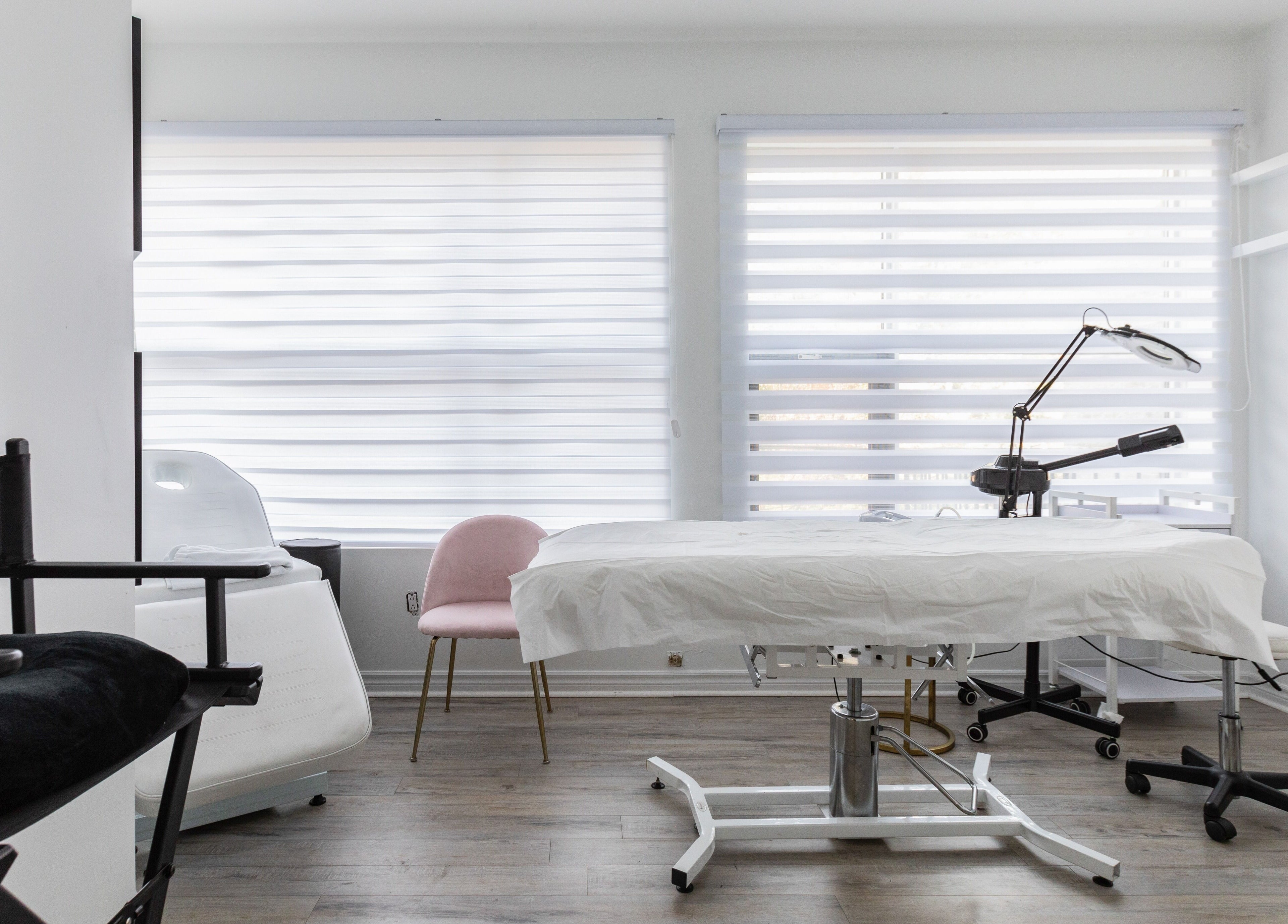Salle lumineuse de soins à Chez Coco Esthétique, Montréal, Québec, CA, avec lit de traitement et chaise élégante.