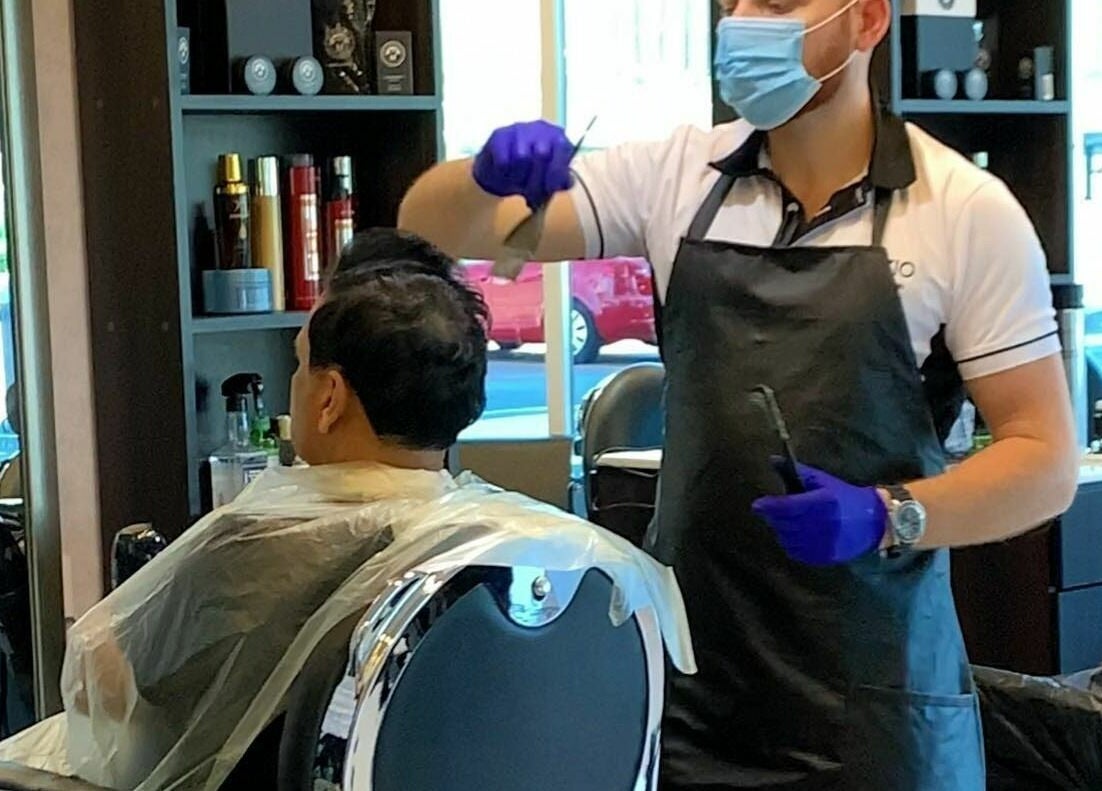 Stylist at Sfizio Gent's Salon, Al Khail Branch, Dubai, AE skillfully cuts a client's hair.