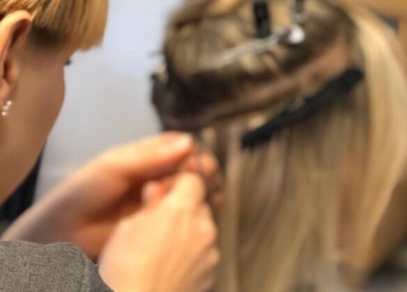 Stylist applying hair extensions at Hair Extensions by Rebecca Banham, Spilsby, England, GB.