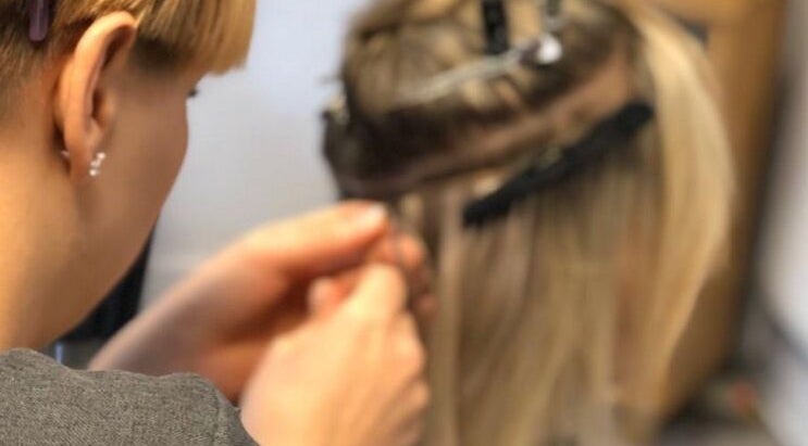 Stylist applying hair extensions at Hair Extensions by Rebecca Banham, Spilsby, England, GB.