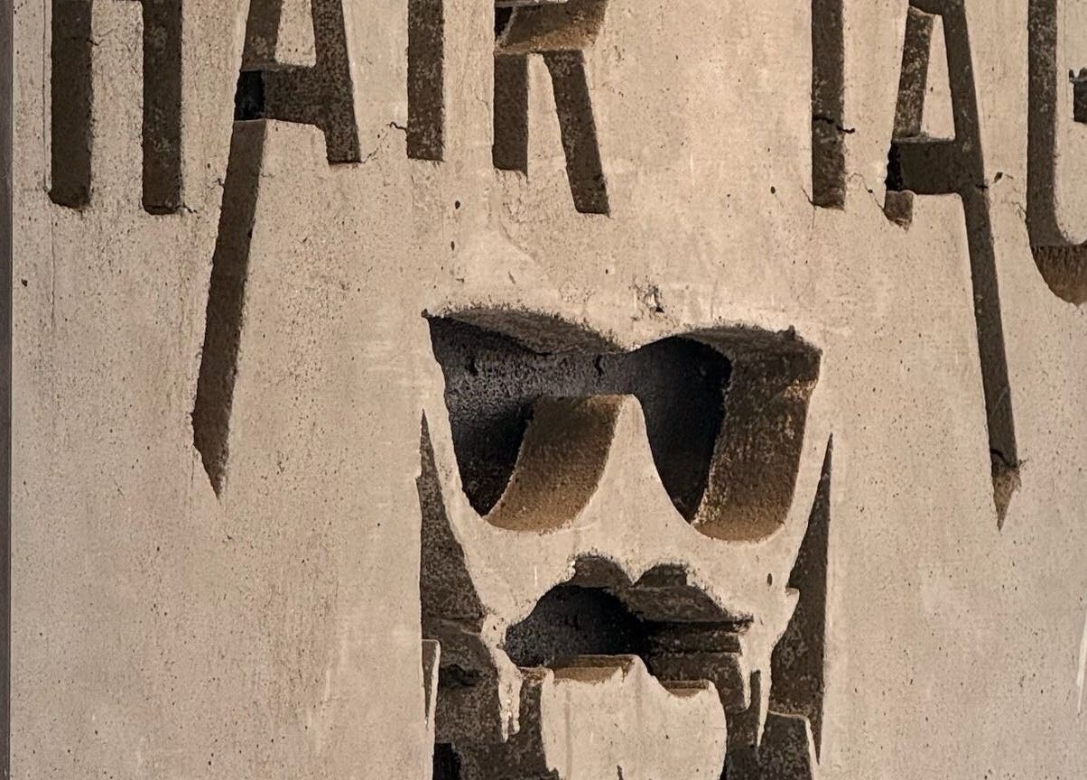 Bold concrete sign of Hair Tag - Al Jaddaf in Dubai, AE, featuring stylish sunglasses motif.