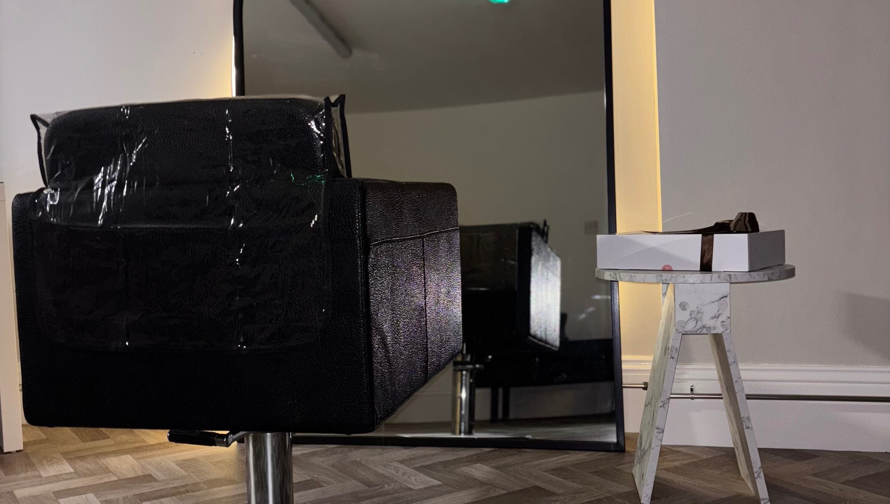 Sleek black chair and marble table at Roxy Hairdressing, Birkenhead, England, GB. Modern salon setting.