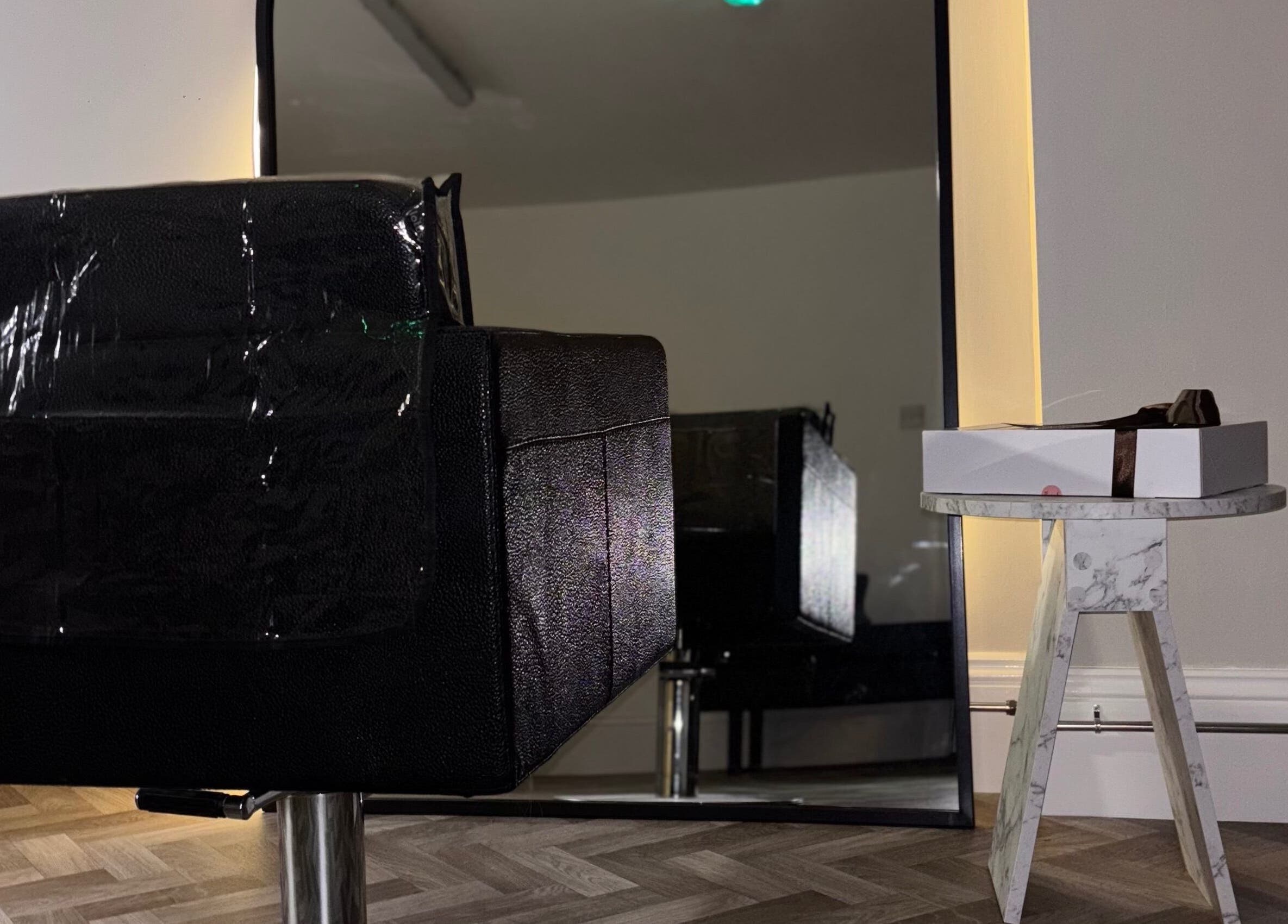 Sleek black chair and marble table at Roxy Hairdressing, Birkenhead, England, GB. Modern salon setting.