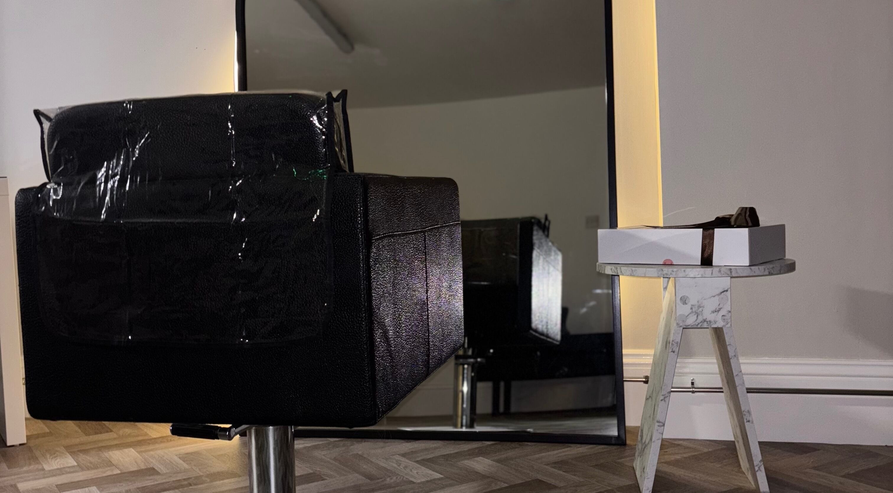 Sleek black chair and marble table at Roxy Hairdressing, Birkenhead, England, GB. Modern salon setting.