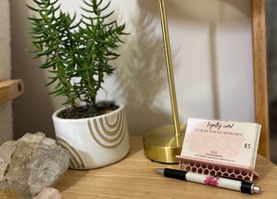 A calming setup at The Body Palette in Coffs Harbour, New South Wales featuring plant, stones, and a loyalty card.