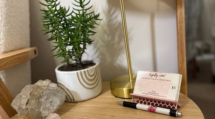 A calming setup at The Body Palette in Coffs Harbour, New South Wales featuring plant, stones, and a loyalty card.