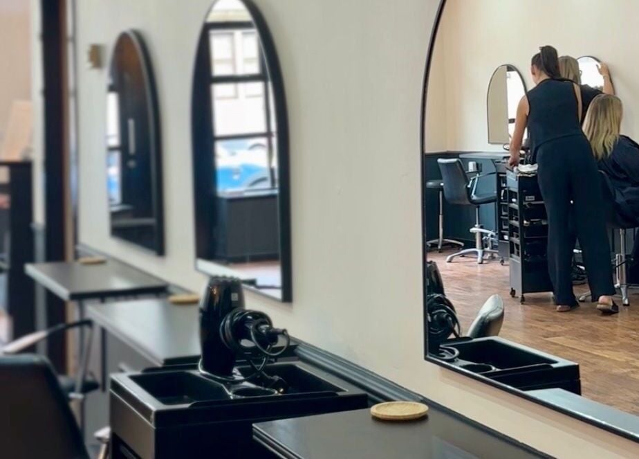Inside SC Hairdressing, Clydebank, Scotland. Elegant salon interior with mirrors and a stylist at work.