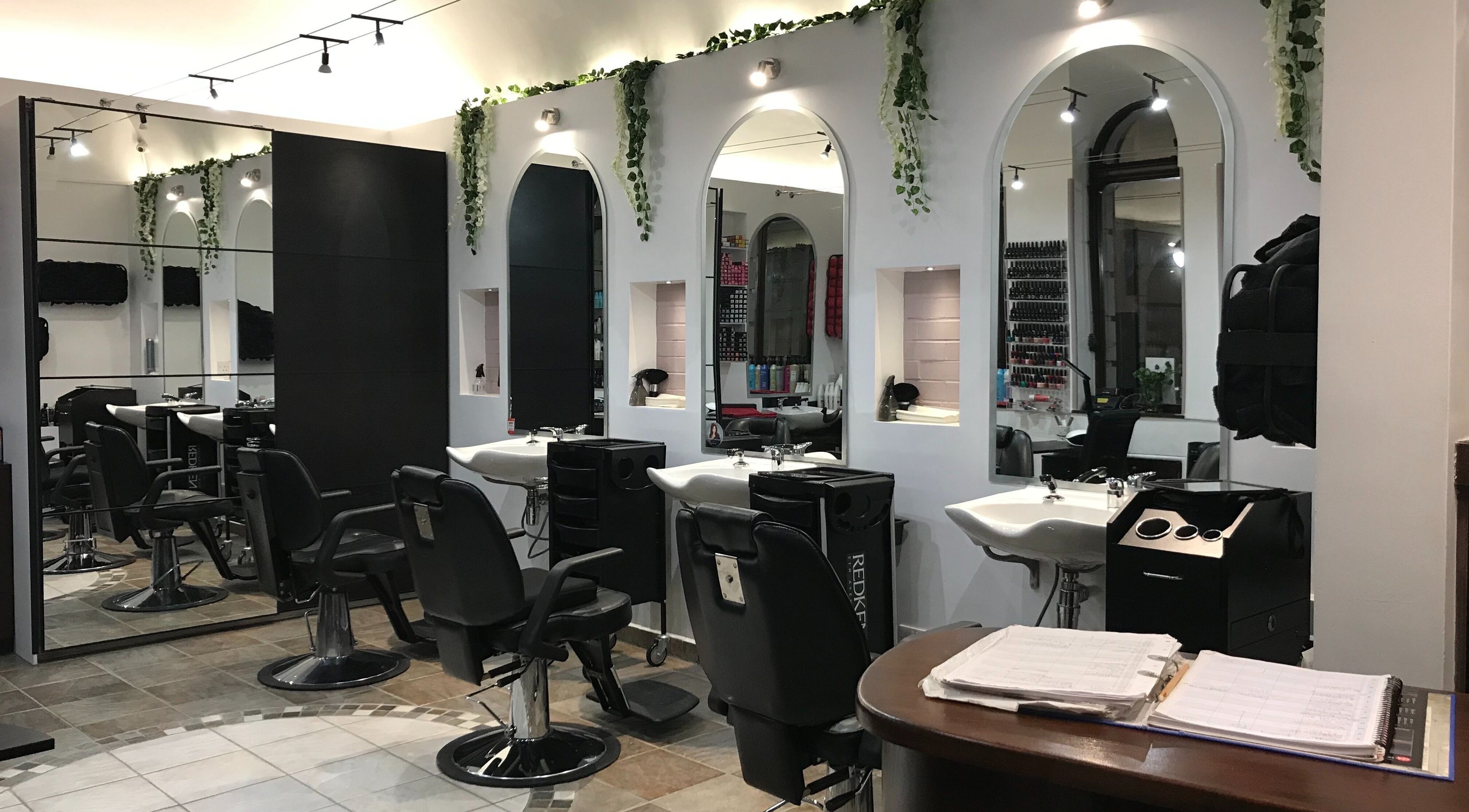 Elegant styling stations at Forever Us Hair and Nail Salon in London, England, GB with lush green accents.