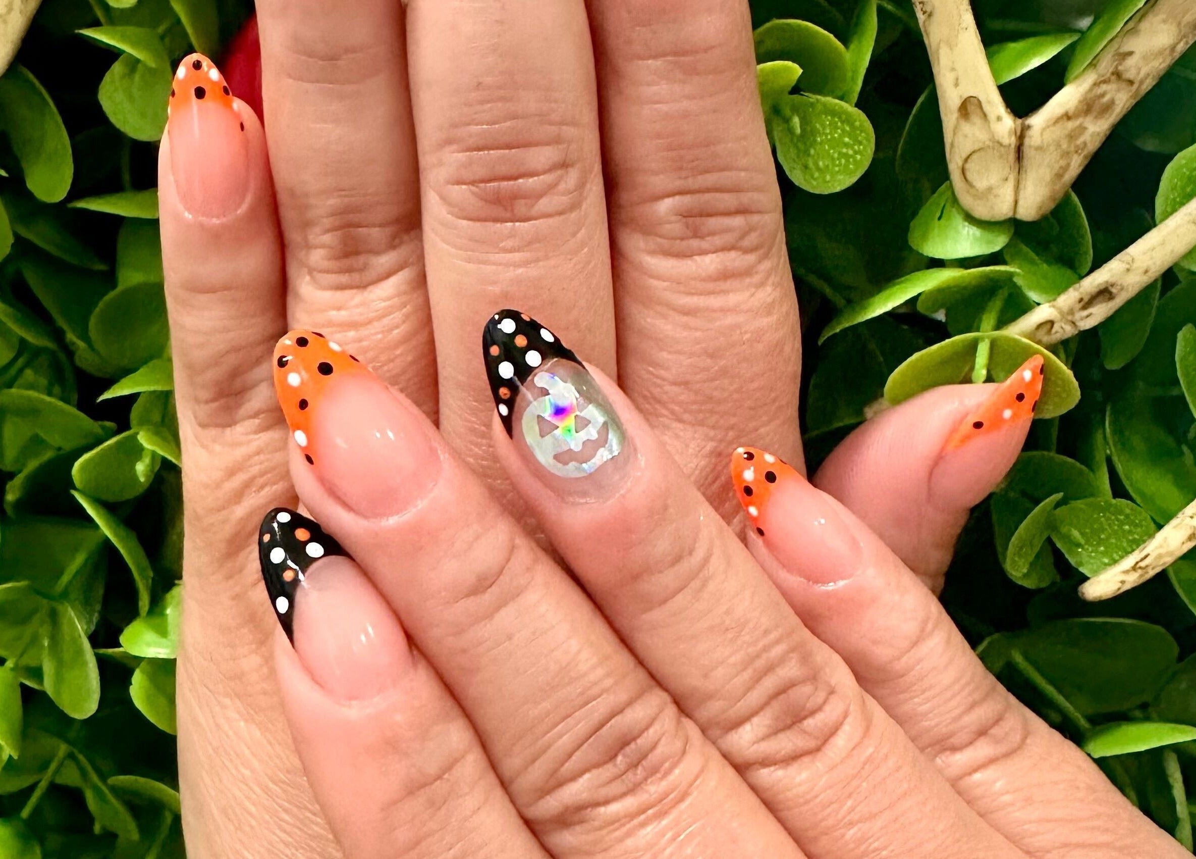 Festive nail art with orange and black polka dots at Lovely Me Nail Studio, Laredo, Texas, US.