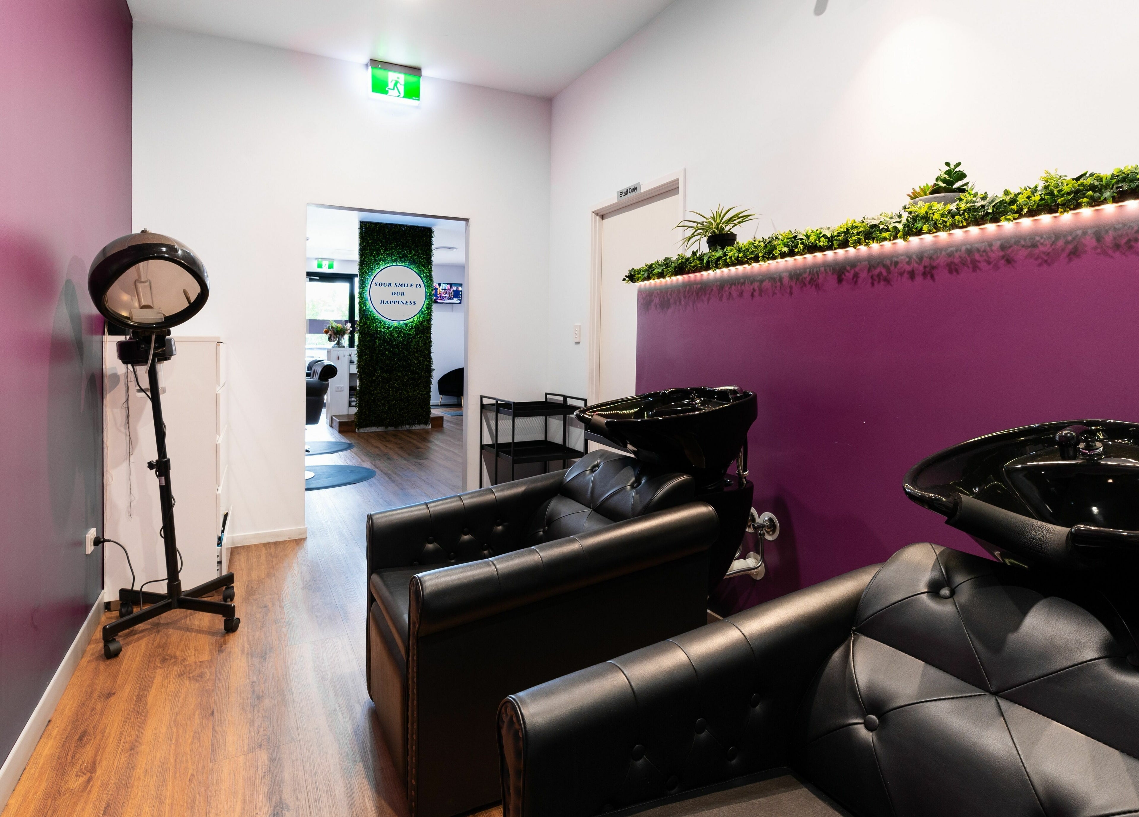 Modern salon interior at Totoya African Hair, Richlands, Queensland, AU, with purple walls and sleek black chairs.