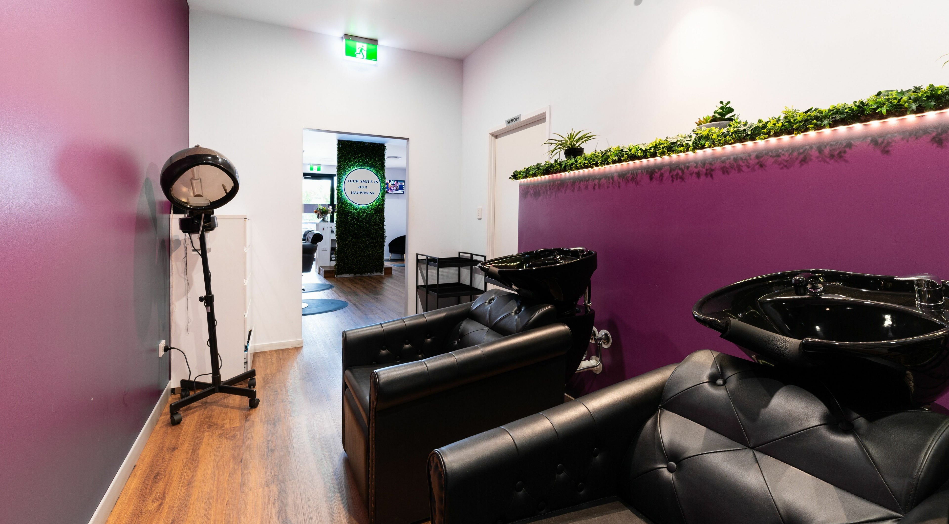 Modern salon interior at Totoya African Hair, Richlands, Queensland, AU, with purple walls and sleek black chairs.