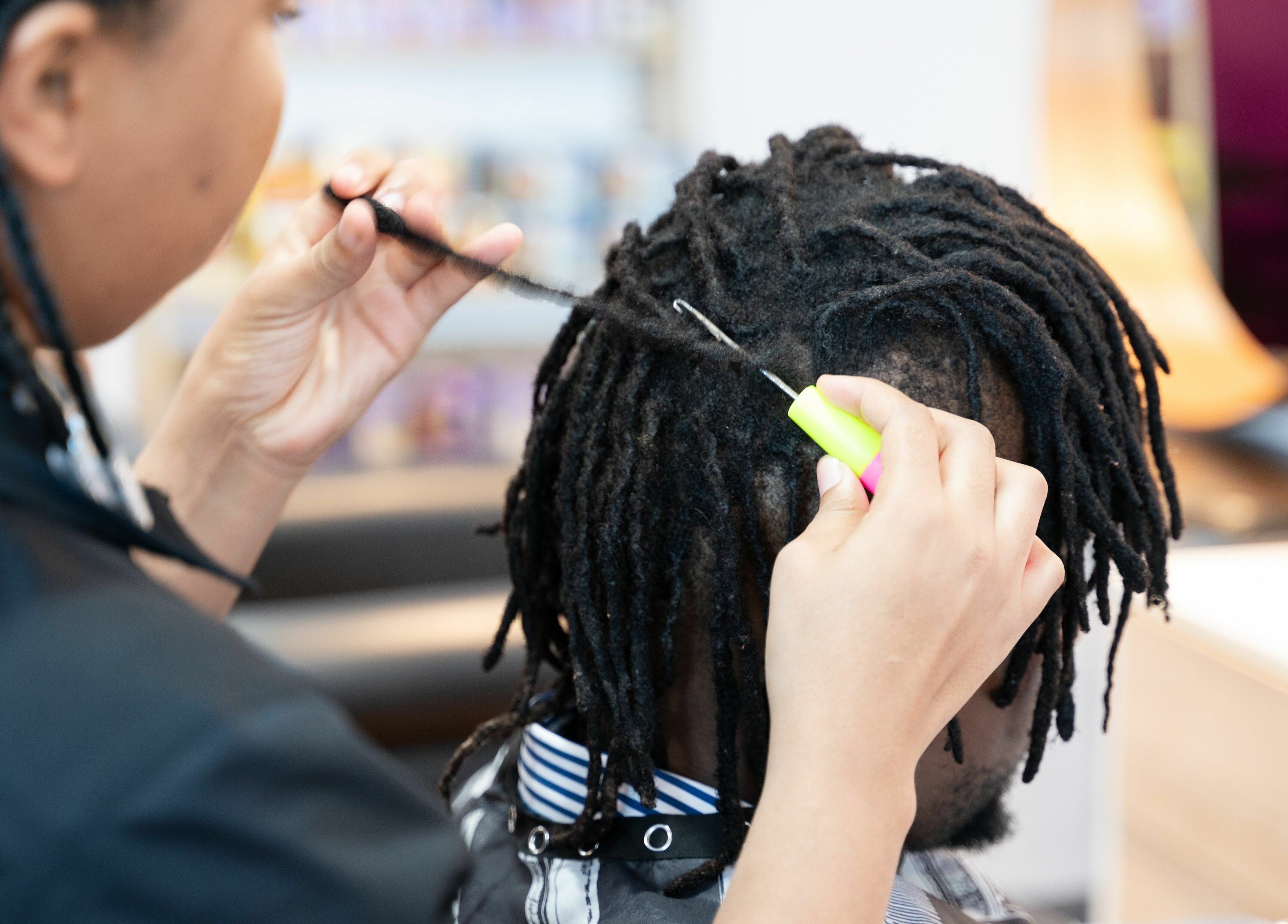 Hairdresser braiding hair at Totoya African Hair, Richlands, Queensland, AU.