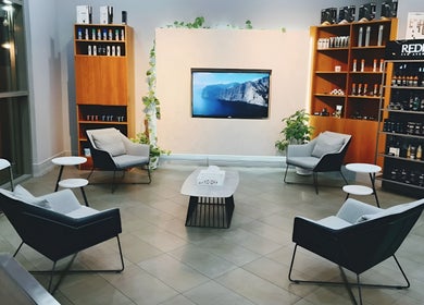 Stylish seating area in Volume Gents Salon, Dubai, AE with modern chairs and shelves filled with products.