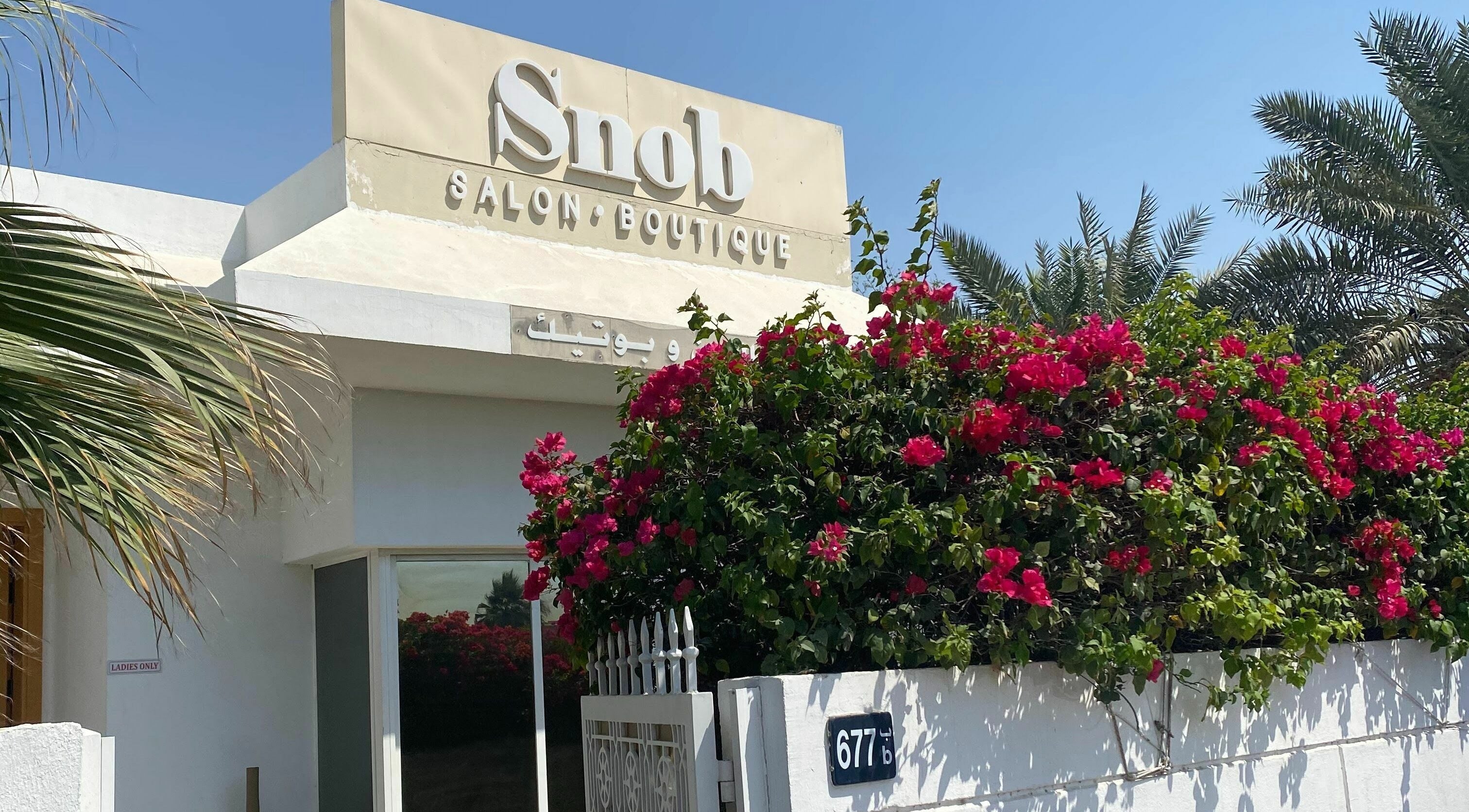 Entrance of Snob Salon and Boutique adorned with vibrant flowers in Dubai, AE.