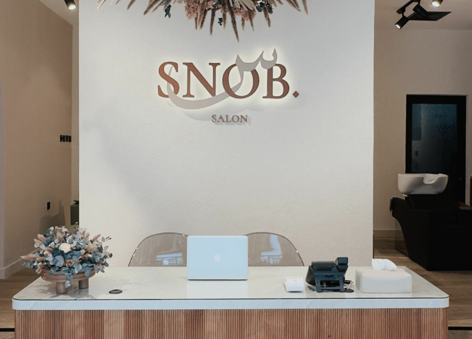 Reception area at Snob Salon Arjan, دبي, دبي, AE featuring minimalist decor and floral accents.