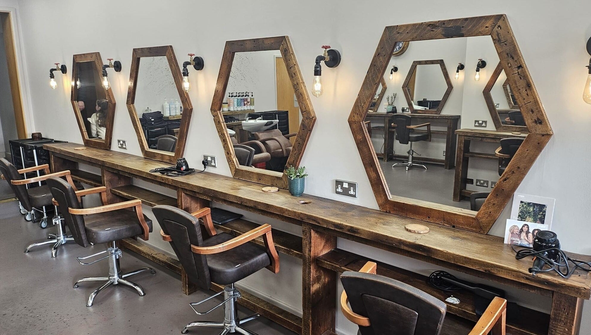 Hexagonal mirrors and wooden styling stations at Her Studio, Grimsby, England, GB. Inviting salon ambiance.