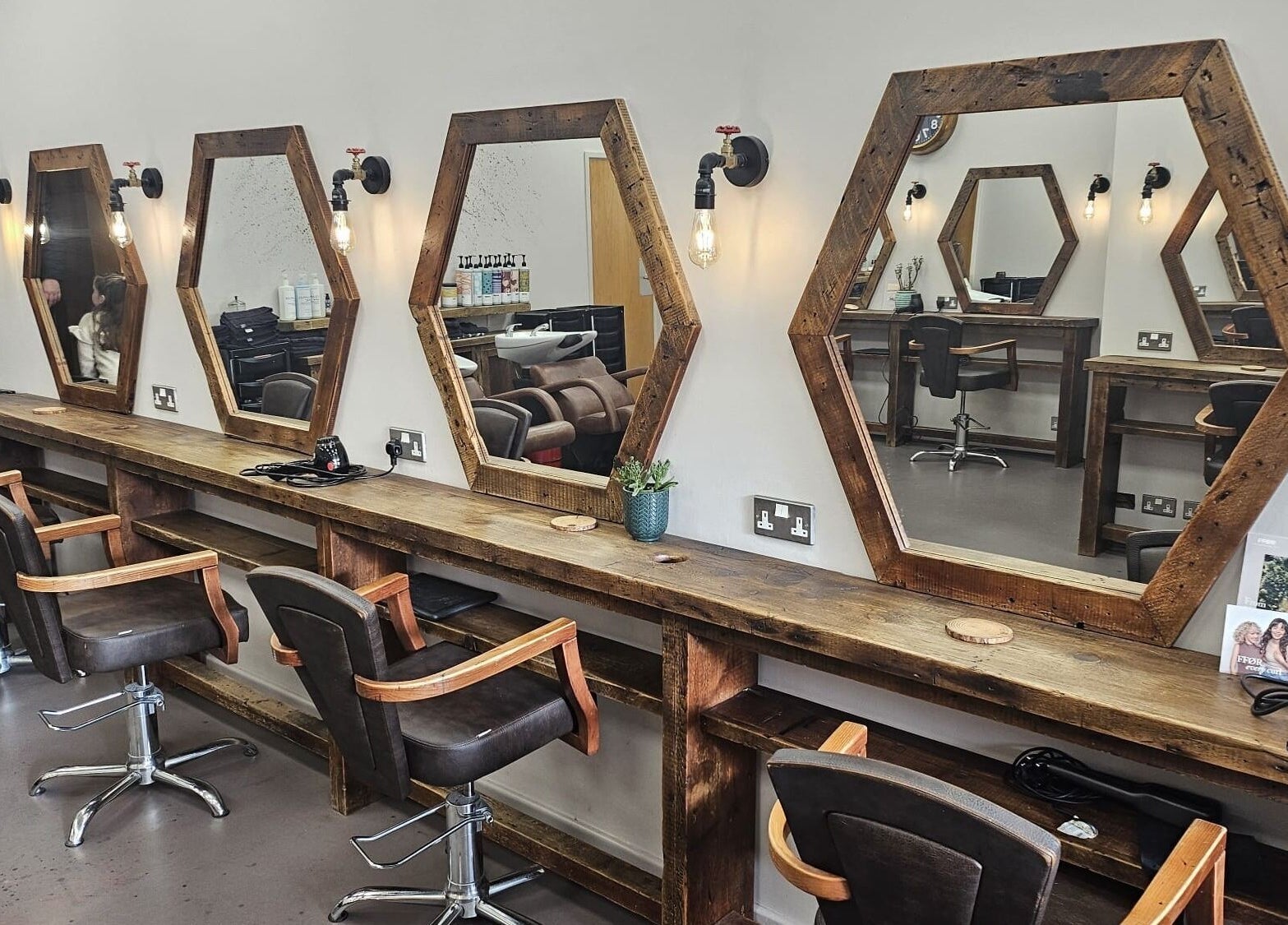 Hexagonal mirrors and wooden styling stations at Her Studio, Grimsby, England, GB. Inviting salon ambiance.