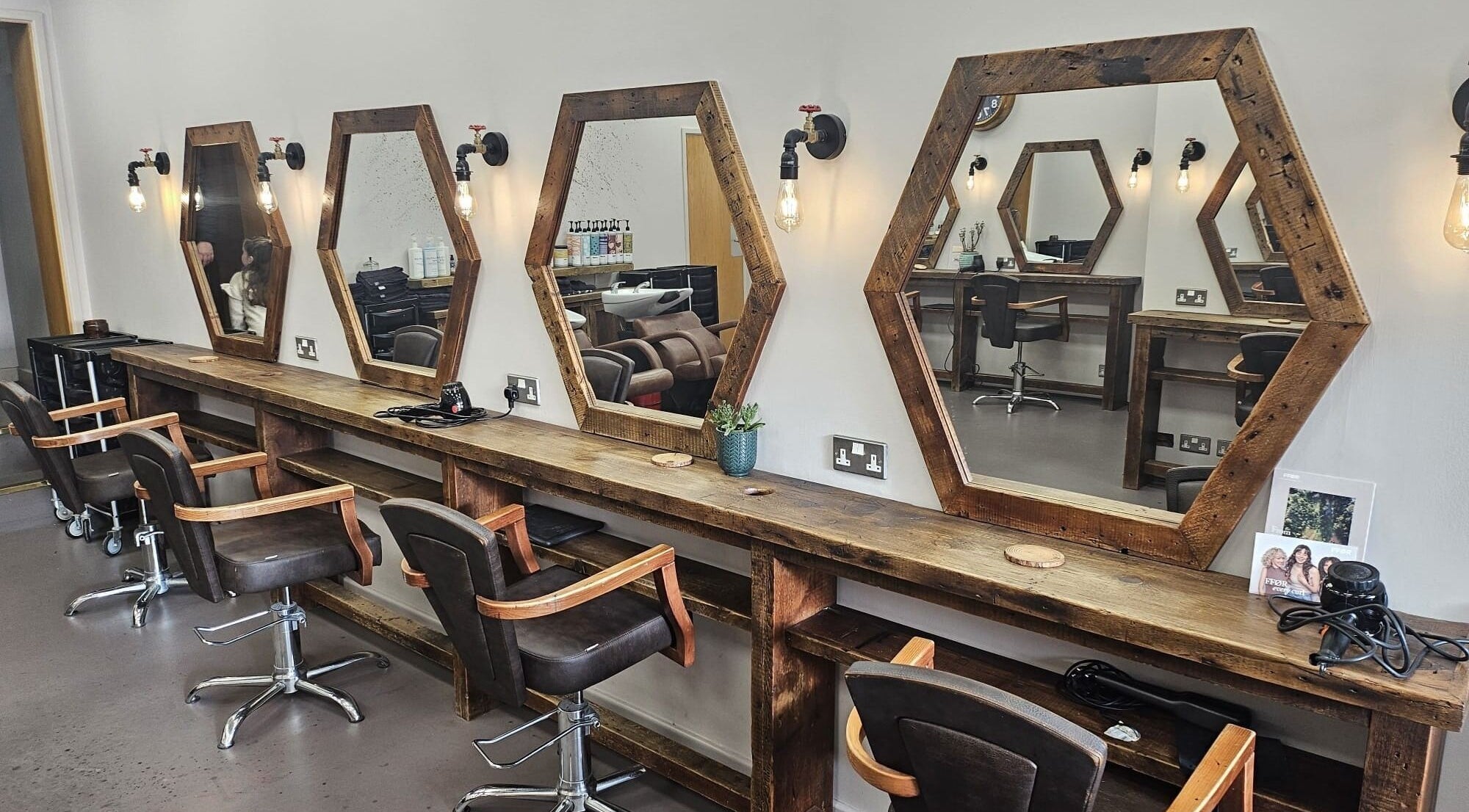 Hexagonal mirrors and wooden styling stations at Her Studio, Grimsby, England, GB. Inviting salon ambiance.