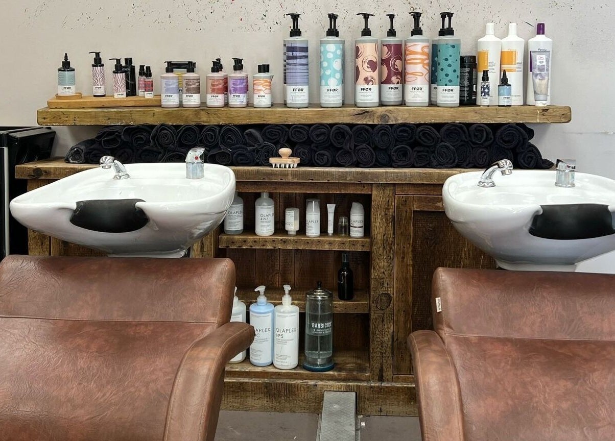 Modern wash station at Her Studio, Grimsby, England, with products neatly displayed and leather chairs.