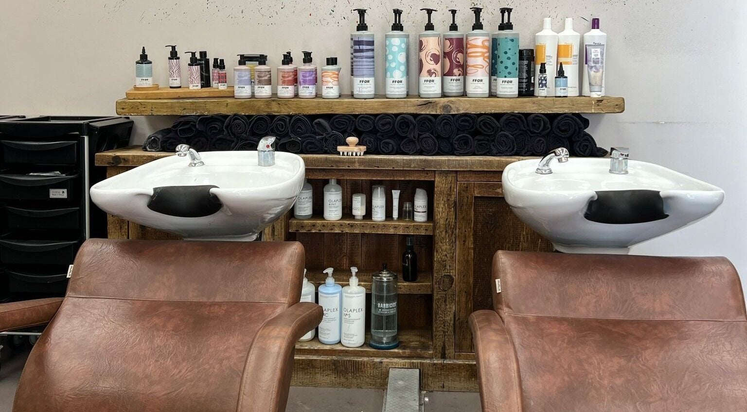 Modern wash station at Her Studio, Grimsby, England, with products neatly displayed and leather chairs.