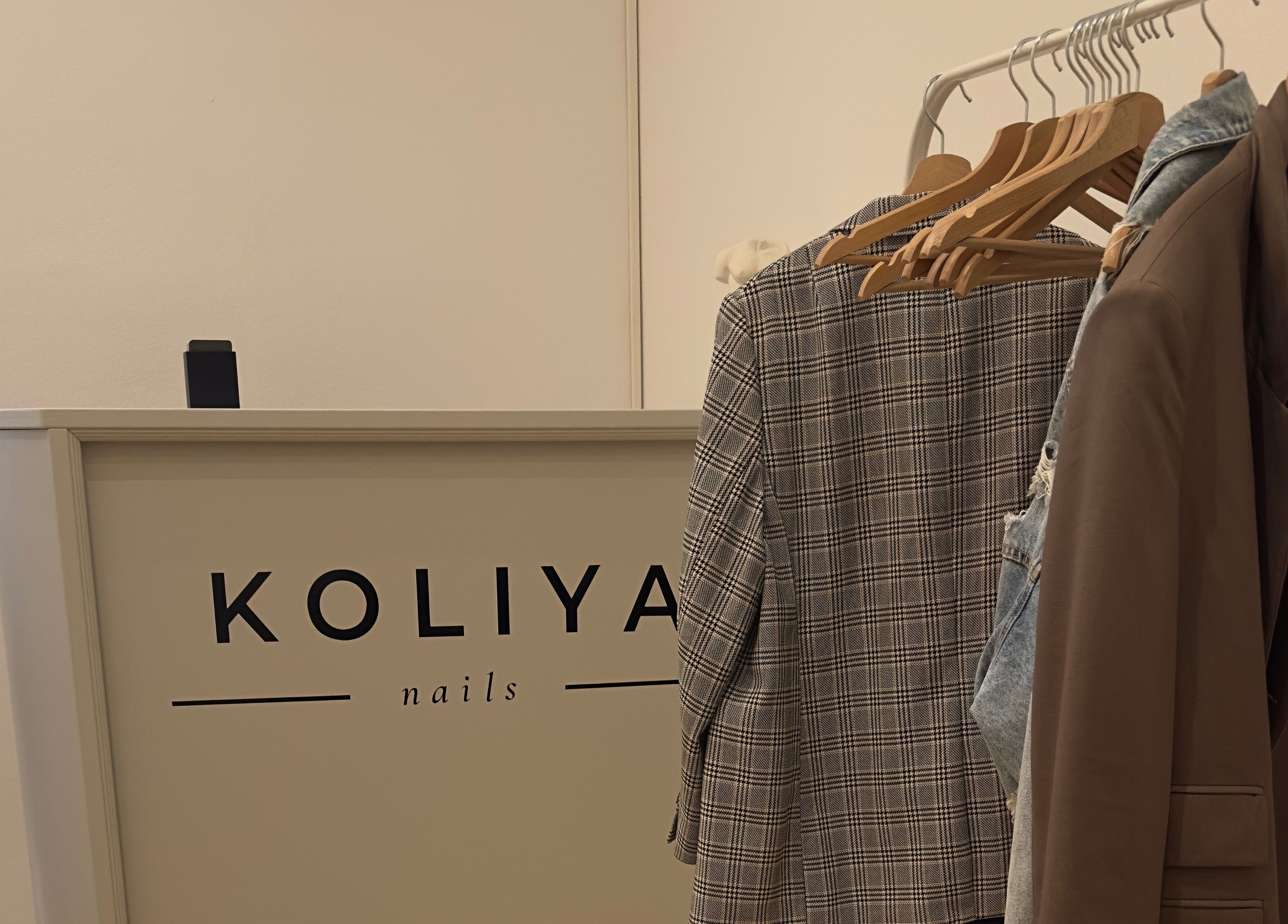 Entrance display at Koliya Nails, Wien with elegant coat racks and reception desk.